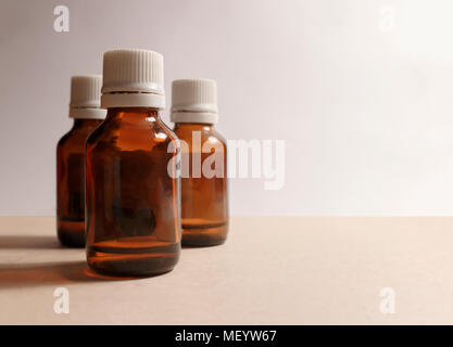 three bottles of medicine on a gray background and a brown table Stock Photo