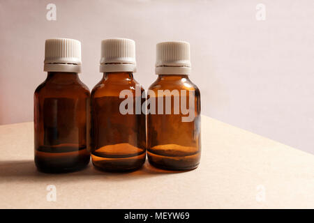three bottles of medicine on a gray table and a pink background Stock Photo