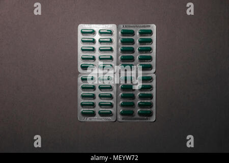 Four blisters of green medicine drugs squared on a cardboard Stock Photo