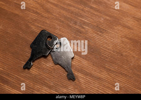 Two small keys on the old wooden table with a lot of scratches. Image with copy space. Stock Photo