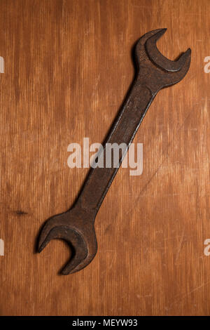 Old rusty spanner on the scratched wooden background. One wrench on the table with copy space Stock Photo