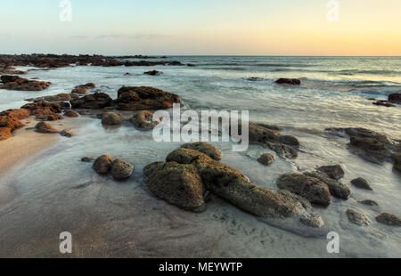 Rocky beach uncovered in low tide after evening sunset. Stock Photo