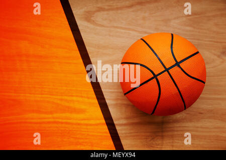 Basketball ball laying on hardwood court floor, top view Stock Photo