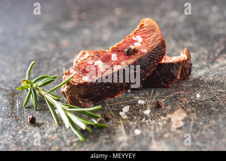 Sliced medium rare grilled steak on old kitchen table. Stock Photo