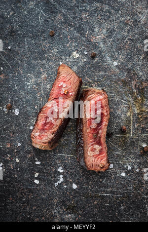 Sliced medium rare grilled steak on old kitchen table. Stock Photo