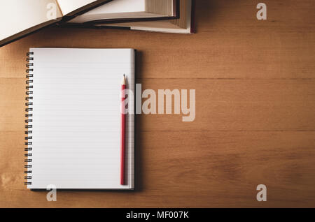 Overhead of desk study scene with pencil on blank page of opened notebook and stack of text books. Filtered with warm, retro effect. Stock Photo