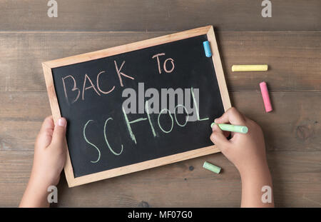 Little hand writing back to school on black chalk board., Back to school and education concept Stock Photo