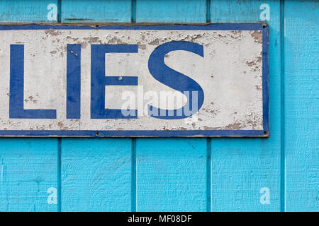 "LIES" – part of a sign on a turquoise blue painted wooden wall Stock Photo