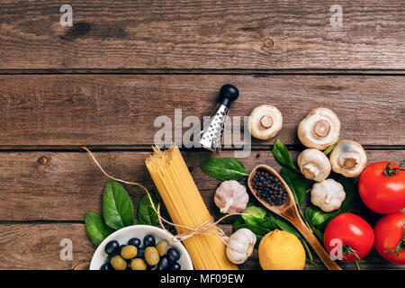 Pasta ingredients - tomatoes, olive oil, garlic, italian herbs, fresh basil, salt and spaghetti on a wooden background with copy space, horizontal, top view Stock Photo
