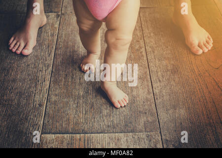 Baby leaning walking with mother, vintage toned. Stock Photo