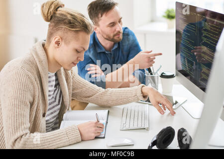 Smart young colleagues discussing programming code Stock Photo