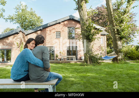Smiling affectionate couple sitting in garden of their home Stock Photo