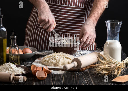 Male chef whipping eggs in the bakery on wooden table. Ingredients for cooking flour products or dough Stock Photo