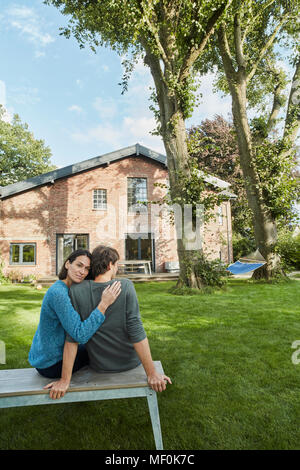 Affectionate couple sitting in garden of their home Stock Photo