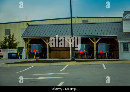 Pennsylvania, USA, APRIL, 18, 2018: Outdoor view of bluured Amish buggies parked under a wooden structure on Lancaster County farm Stock Photo