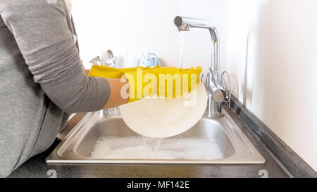 Closeup image of young woman washing dishes under flowing water Stock Photo