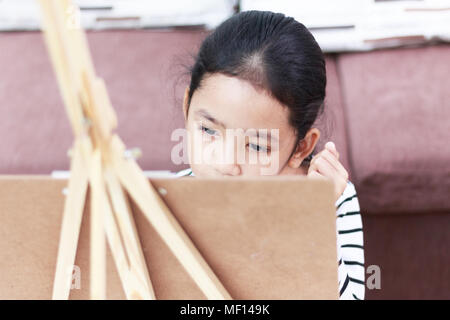 dreamy girl and hand girl holding a red paintbrush draws picture at home Stock Photo