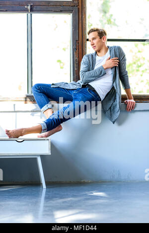 A young handsome male Dancer resting in a modern Loft Apartment Stock Photo