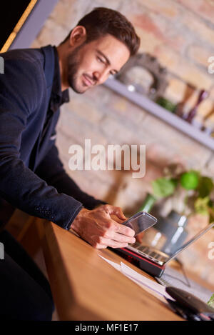 A happy handsome young businessman using his smartphone in office environment. Stock Photo