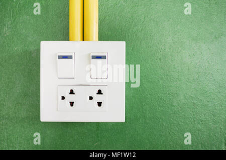 Plug and socket on wall as green background Stock Photo