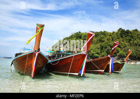 Thai fishing boats tied up on the beach with a beautiful island in the background, Krabi, Thailand. Stock Photo