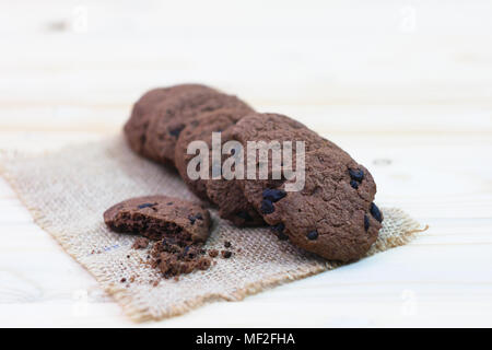 Chocolate chip cookies with a bite mark placed on a sack on a wooden table. Stock Photo