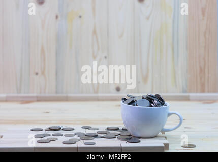 coins in a white coffee cup is placed on a wooden table and around a cup Stock Photo