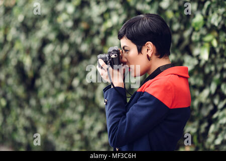 Fashionable young woman taking photo with camera Stock Photo