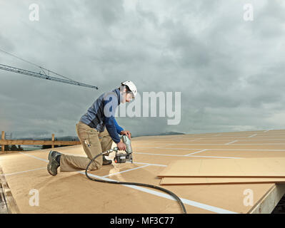 Austria, construction worker fixing medium-density fibreboard Stock Photo