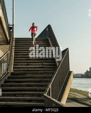 Young woman running up stairs at a river Stock Photo