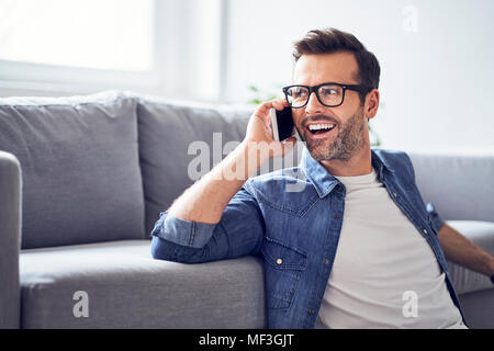 Happy man in living room talking on cell phone Stock Photo