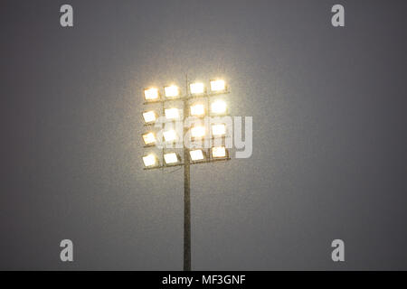 Stadium lights on pole, outdoors, snowy night. Dark sky in contrast to intense lights. Stock Photo