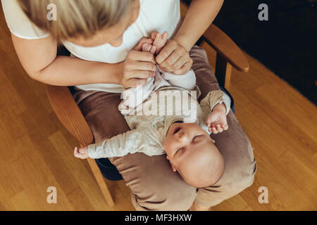 Mother holding up baby‚Äôs feet to help with digestion Stock Photo
