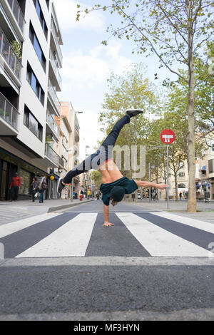 Back view of young man doing handstand on zebra crossing Stock Photo