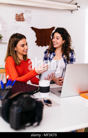 Two fashion designers working in studio with laptop and notebook Stock Photo