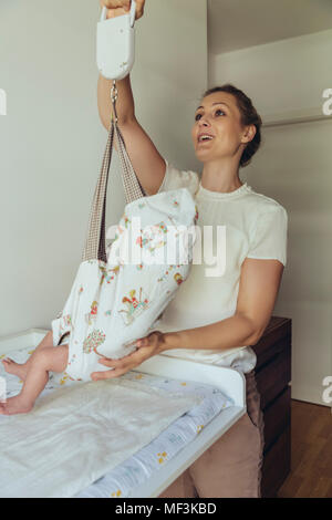 Midwife using baby scales to weigh newborn Stock Photo