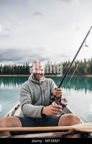 Portrait of happy man fishing in canoe on boya lake hi-res stock