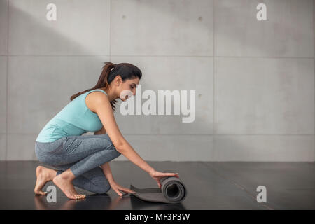 Young woman preparing for yoga exercise in studio Stock Photo