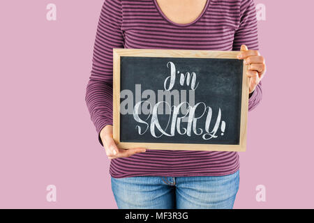 Female hands holding small black chalkboard in front of the body with written words saying I'm Sorry Stock Photo