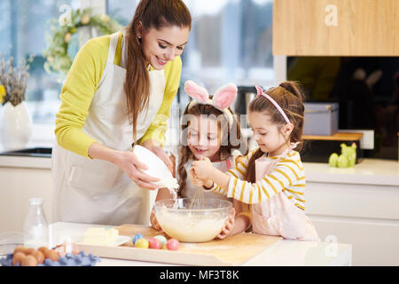 Mother and daughters baking Easter cookies in kitchen together Stock Photo
