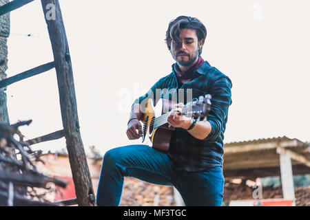 Young man playing guitar outdoors on a farm Stock Photo