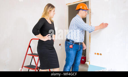 Construction worker showing new house to beautiful young businesswoman Stock Photo