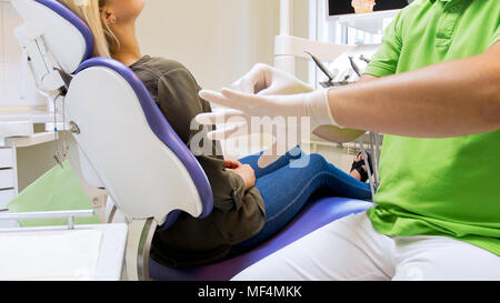 Closeup image of dentist wearing protective latex gloves on hands Stock Photo