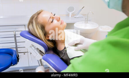 Closeup portrait of beautiful blonde woman with tissue lying in dentist chair Stock Photo