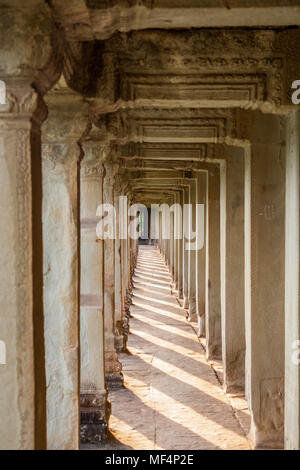 Inside the outer corridor of Angkor Wat, Siem Reap, Cambodia. The columns cast their shadows on to the floor made of big stone slabs. Stock Photo