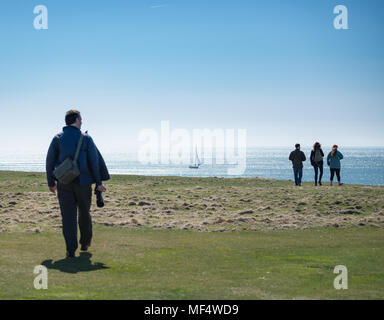 People walking at Sound, view toward sea with distant sailing boat Stock Photo