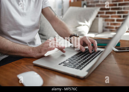 Man's hands on keyboard and touchpad of laptop, partial view Stock Photo
