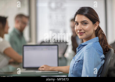 Portrait of smiling businesswoman with laptop during a meeting in office boardroom Stock Photo