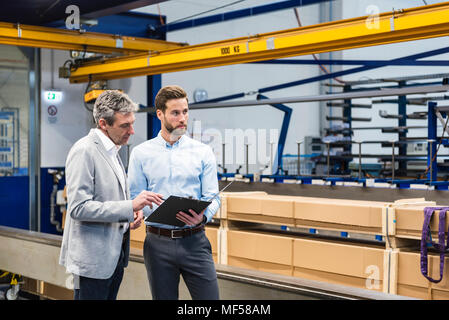 Businessmen during meeting with clipboard in production hall Stock Photo