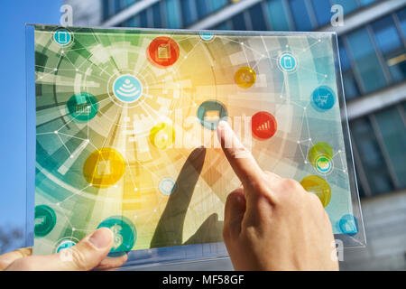 Hand holding futuristic device with digital icons Stock Photo
